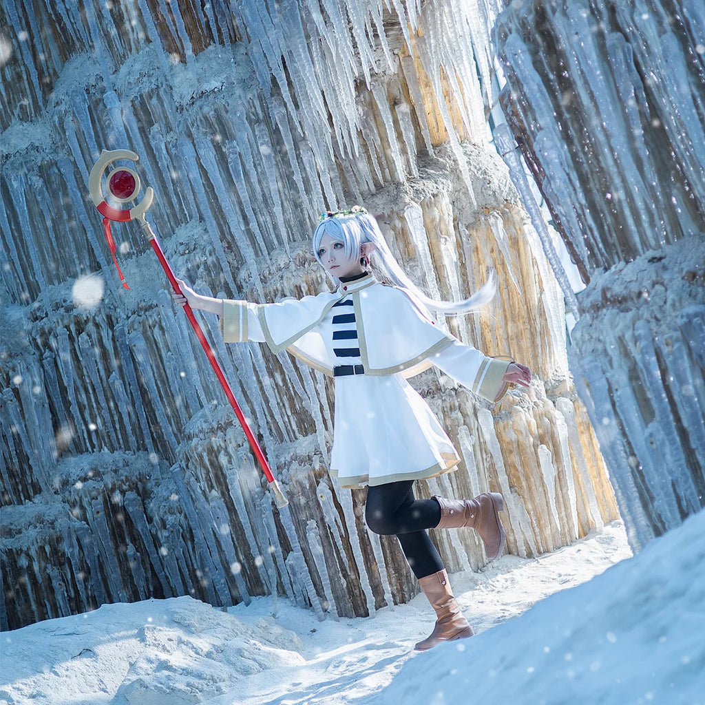 Person in a white outfit with a red staff standing in front of ice formations